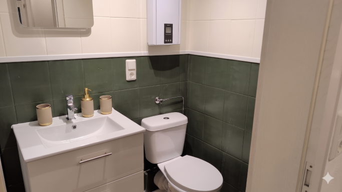 Badezimmer Badezimmer mit Waschbecken, Toilette und grün gefliester Wand.