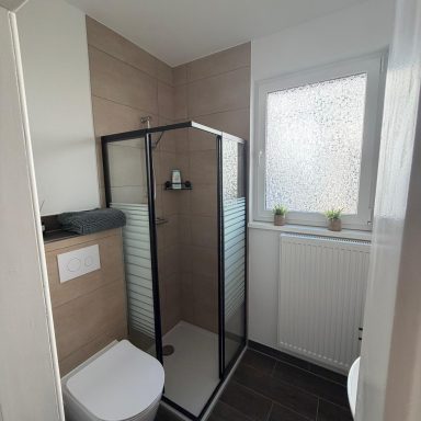 Kleines modernes Badezimmer mit Dusche, Waschbecken und Fenster.