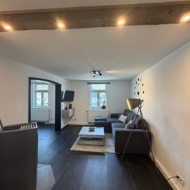 Helles Wohnzimmer mit Sofa, Couchtisch und Fernseher, moderne Einrichtung.