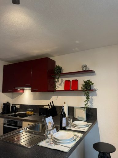 Moderne Küche mit rotem Schrank, Geschirr und einem Tisch für zwei Personen.