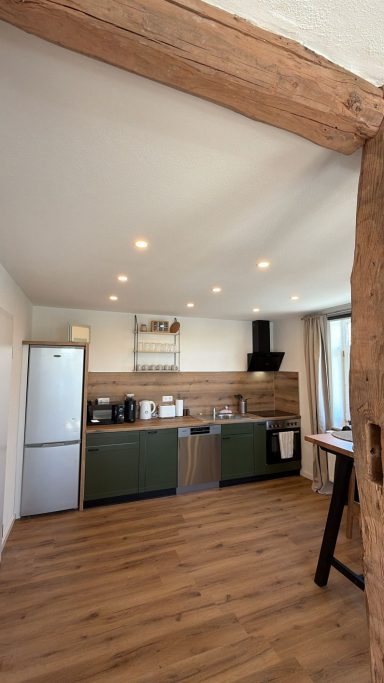 Küche Moderne Küche mit Holzdetails, grünen Schränken und Holzboden.