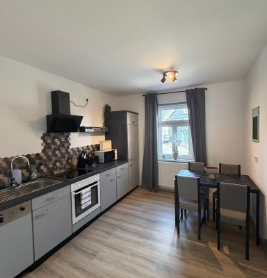 Moderne Küchenzeile mit Esstisch und Stühlen, Fenster mit Tageslicht.