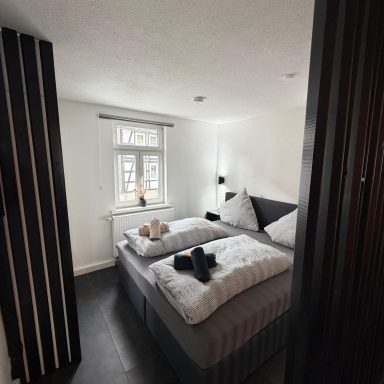Helles Schlafzimmer mit zwei Betten, modernen Möbeln und Fensterlicht.